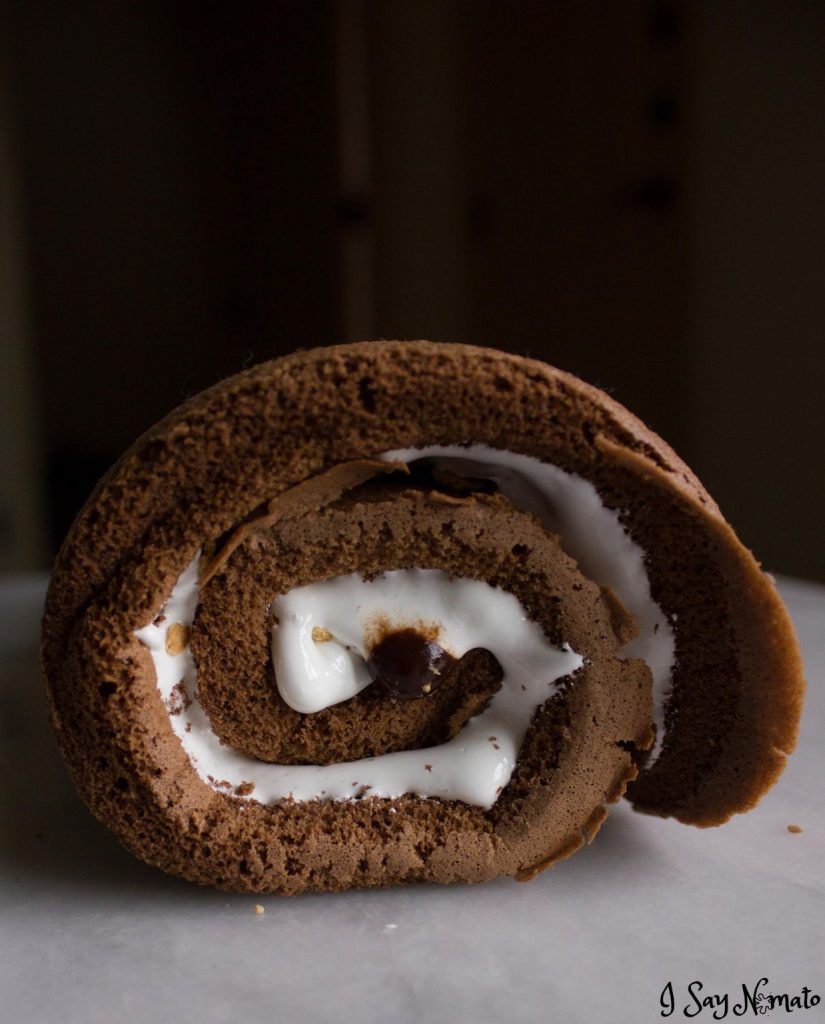This S'mores Swiss Roll is filled with marshmallow fluff, sprinkled with crunchy graham crackers, and covered in chocolate ganache for a sweet, camping-inspired treat! 